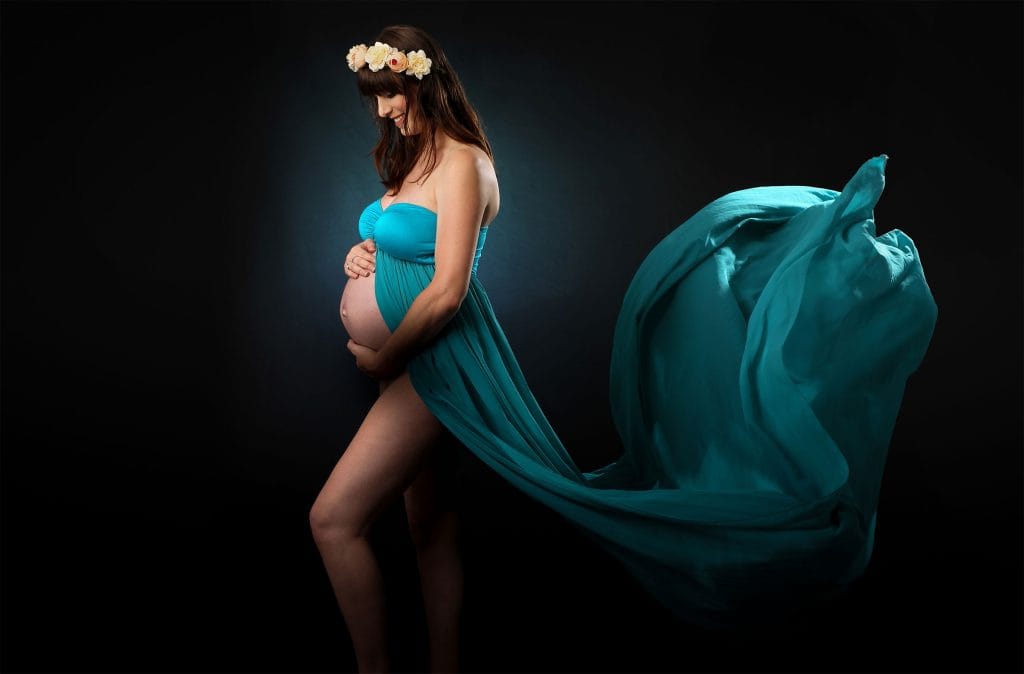 Pregnant woman in teal flowing gown posing for elegant maternity photography on Paul Photos Australia homepage