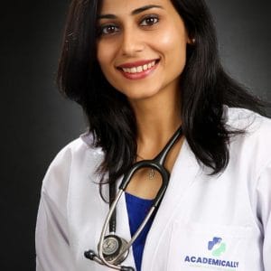 Female doctor smiling in a professional studio portrait wearing a white coat and stethoscope